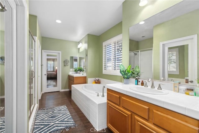 ensuite bathroom with a healthy amount of sunlight, a sink, a shower stall, and a bath