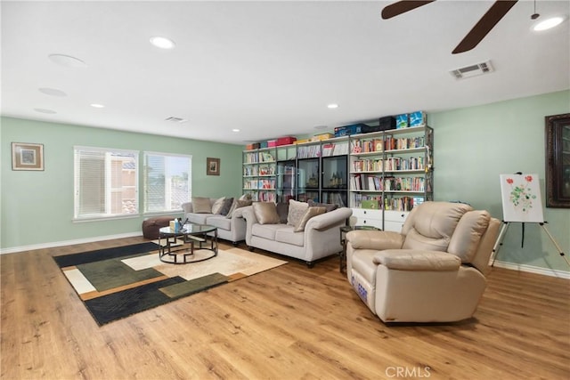 living room featuring baseboards, visible vents, wood finished floors, and recessed lighting