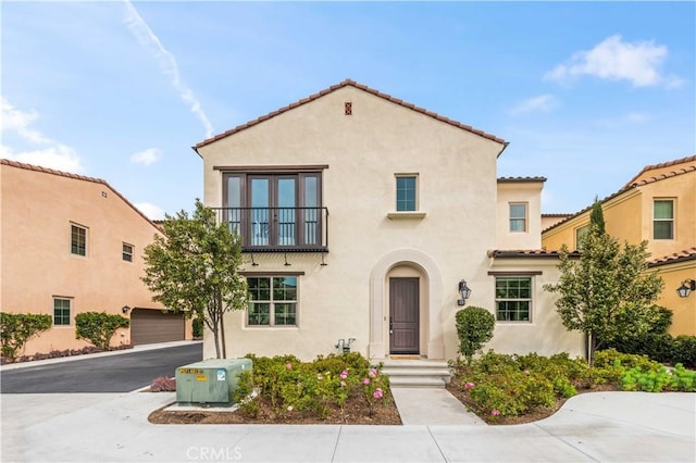 mediterranean / spanish-style house featuring a balcony, a garage, a tile roof, french doors, and stucco siding