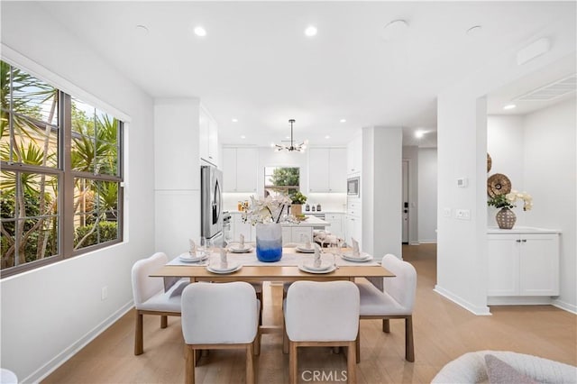 dining space with baseboards, recessed lighting, light wood-style flooring, and an inviting chandelier