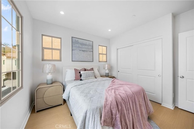 bedroom featuring light wood-style floors, baseboards, a closet, and recessed lighting