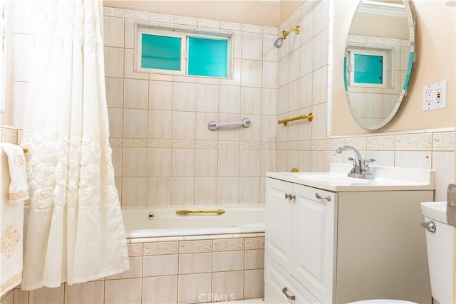 bathroom featuring tiled shower / bath combo, tile walls, and vanity