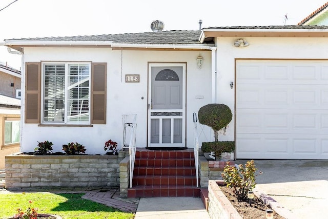 property entrance with a shingled roof, an attached garage, and stucco siding