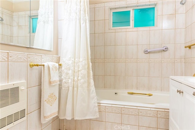 bathroom featuring tile walls, heating unit, tiled shower / bath, and vanity