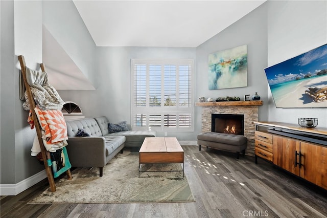 living room featuring a fireplace, baseboards, vaulted ceiling, and wood finished floors