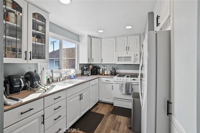 kitchen featuring white appliances, a sink, dark wood finished floors, and white cabinetry