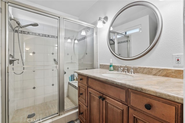 bathroom with a textured wall, a stall shower, and vanity