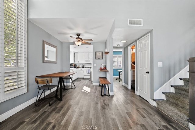 dining space featuring baseboards, visible vents, a ceiling fan, stairway, and dark wood-type flooring