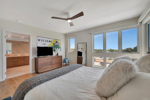 bedroom with ensuite bathroom, light wood finished floors, and a ceiling fan