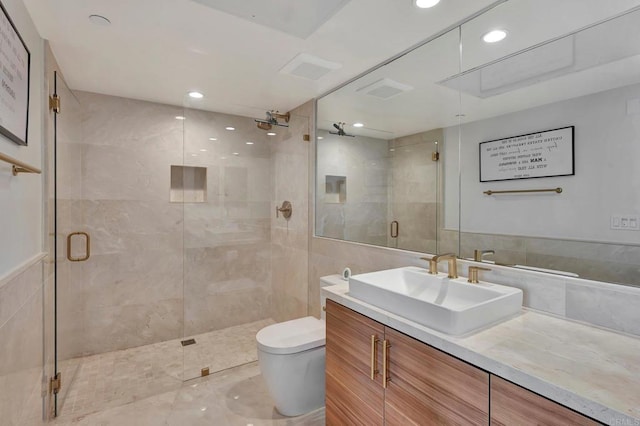 bathroom with toilet, a shower stall, tile walls, and vanity