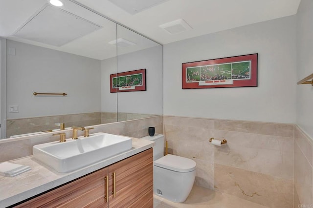 bathroom with toilet, wainscoting, tile walls, and vanity