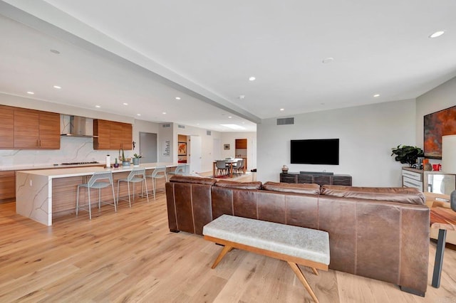 living area featuring visible vents, light wood-style flooring, and recessed lighting