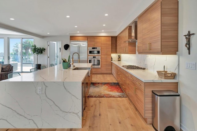 kitchen with stainless steel appliances, brown cabinets, wall chimney exhaust hood, tasteful backsplash, and modern cabinets