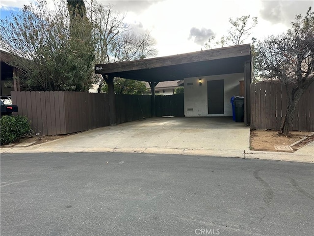 view of vehicle parking with driveway and fence