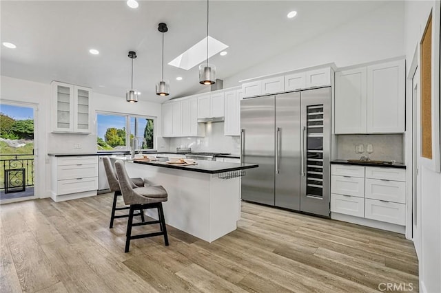 kitchen with dark countertops, light wood-style floors, white cabinets, and stainless steel appliances