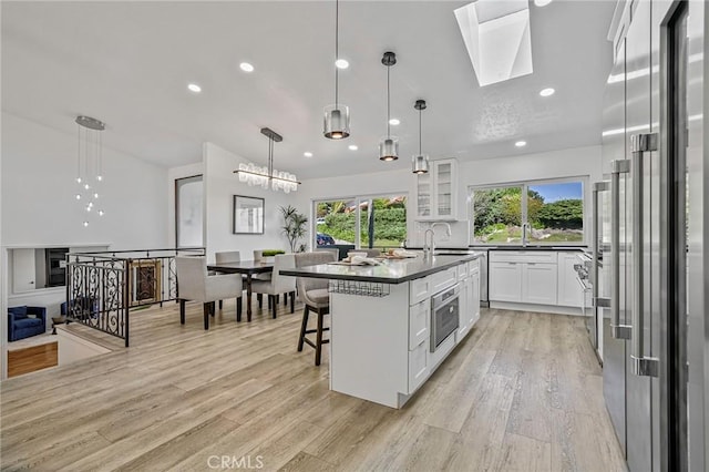 kitchen featuring dark countertops, light wood-style flooring, white cabinets, and stainless steel appliances