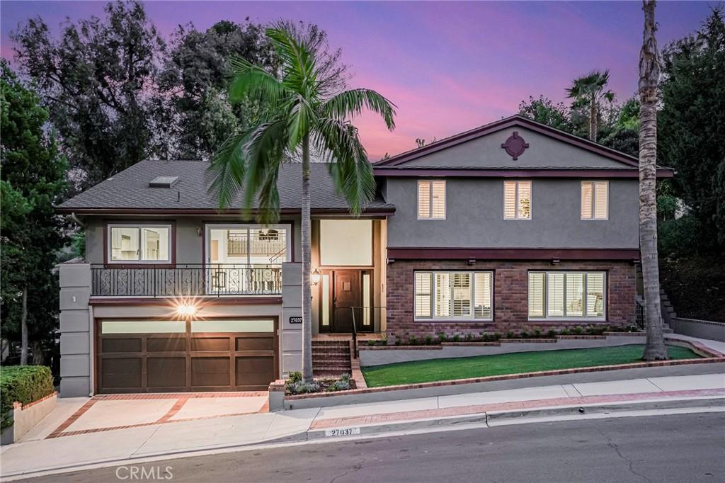 tri-level home featuring driveway, brick siding, an attached garage, and stucco siding