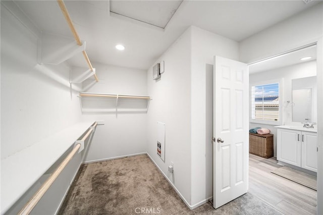 washroom featuring light carpet, laundry area, baseboards, a sink, and recessed lighting