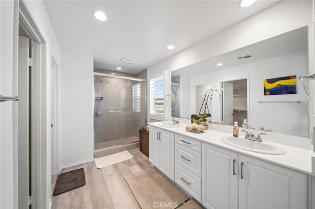 full bath featuring double vanity, a stall shower, a sink, and visible vents