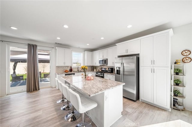 kitchen featuring light wood-style flooring, a kitchen island, appliances with stainless steel finishes, white cabinetry, and a sink