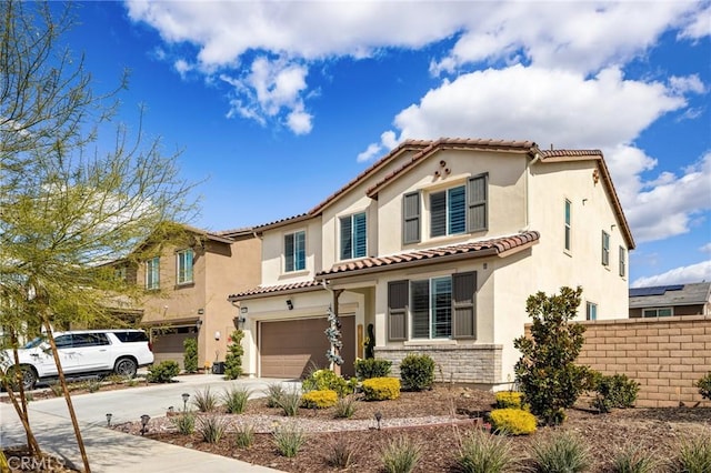 mediterranean / spanish house featuring a garage, fence, concrete driveway, and stucco siding