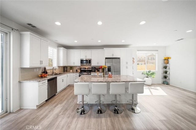 kitchen featuring a sink, appliances with stainless steel finishes, light wood-style flooring, and visible vents