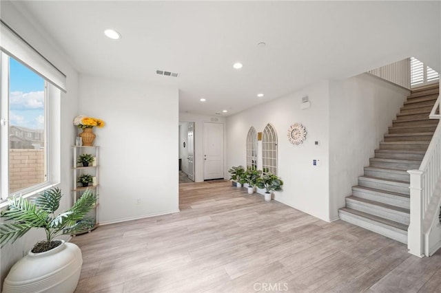 foyer entrance featuring light wood finished floors, stairway, visible vents, and recessed lighting