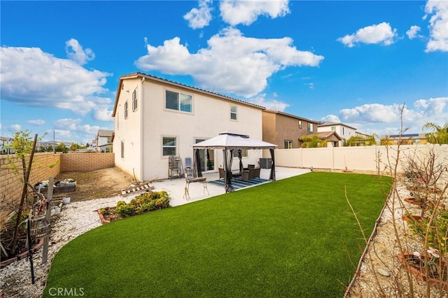 rear view of house featuring a patio, a fenced backyard, a gazebo, a yard, and stucco siding