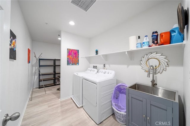 laundry room featuring laundry area, washing machine and clothes dryer, visible vents, and light wood-style floors