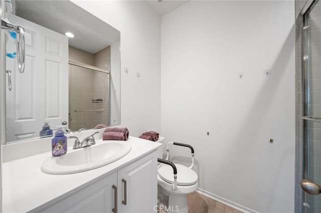 bathroom featuring baseboards, toilet, wood finished floors, a tile shower, and vanity