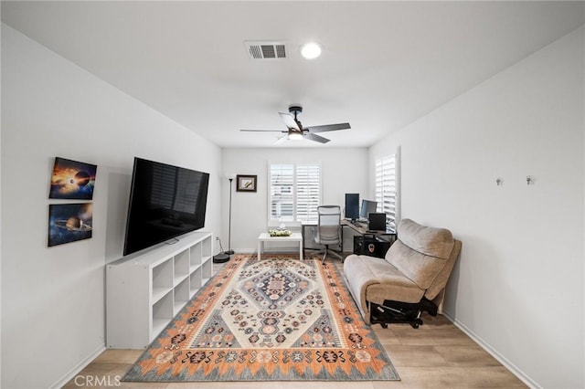 living area featuring light wood-style flooring, visible vents, ceiling fan, and baseboards