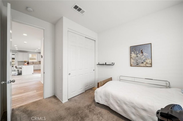 bedroom with a closet, visible vents, carpet, a sink, and recessed lighting