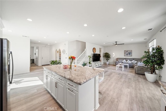 kitchen with light wood-style floors, a center island, and stainless steel fridge with ice dispenser