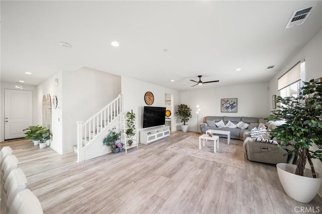 living room featuring recessed lighting, visible vents, light wood finished floors, and stairs