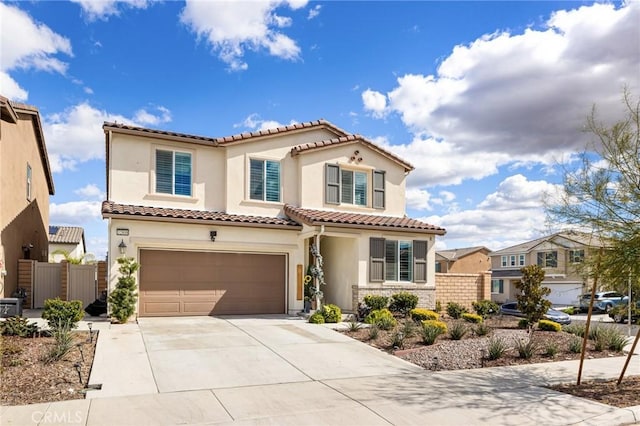 mediterranean / spanish-style home with driveway, an attached garage, fence, and stucco siding