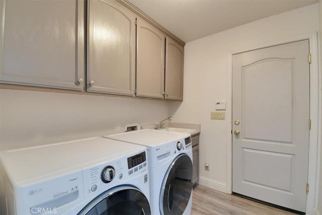 laundry area with baseboards, washer and dryer, light wood-style floors, cabinet space, and a sink