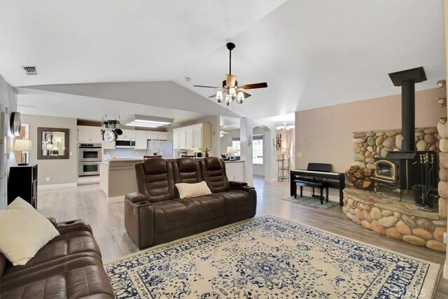 living area featuring visible vents, arched walkways, ceiling fan, vaulted ceiling, and light wood-style floors