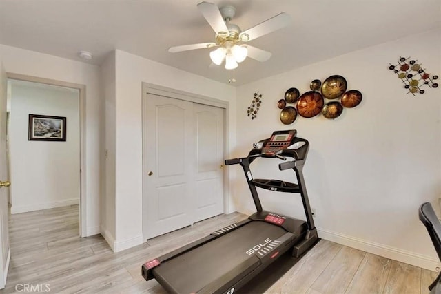 exercise area with light wood finished floors, ceiling fan, and baseboards