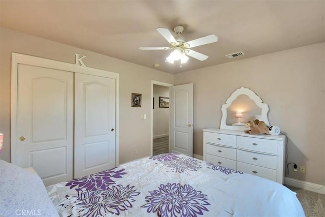 carpeted bedroom featuring a closet, visible vents, baseboards, and ceiling fan
