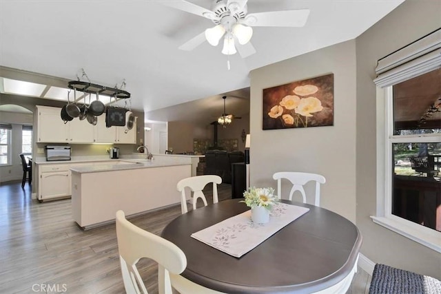 dining space with a ceiling fan, arched walkways, light wood finished floors, and baseboards