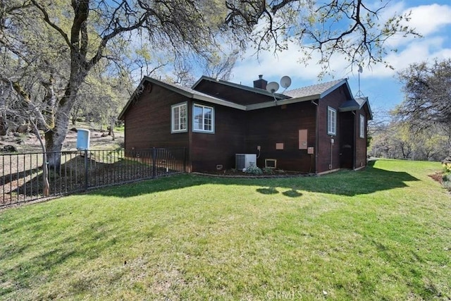 view of side of property with central air condition unit, a lawn, a chimney, and fence