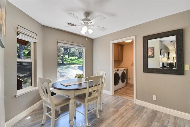dining space with baseboards, light wood finished floors, a healthy amount of sunlight, and washer and clothes dryer