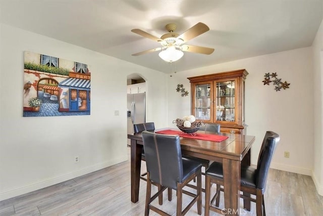 dining area featuring light wood finished floors, a ceiling fan, and baseboards
