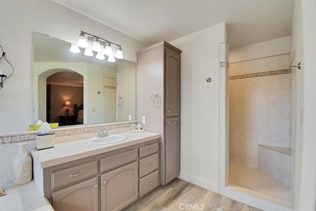 full bathroom with a walk in shower, vanity, ensuite bathroom, and wood finished floors