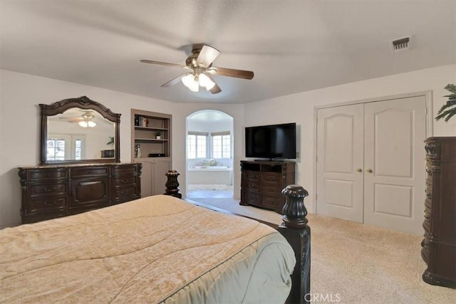 bedroom featuring visible vents, a closet, arched walkways, carpet flooring, and ceiling fan