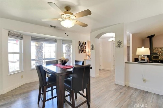 dining area featuring light wood-type flooring, visible vents, arched walkways, and a healthy amount of sunlight