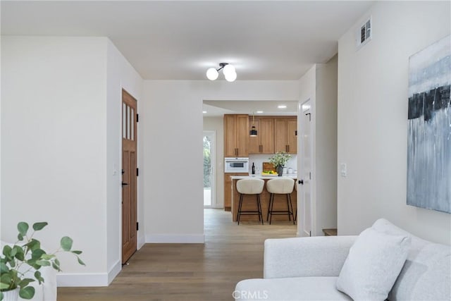 living room featuring light wood finished floors, visible vents, baseboards, and recessed lighting