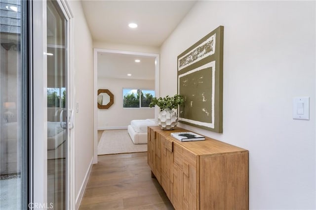 hallway with baseboards, recessed lighting, and light wood-style floors