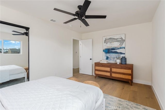 bedroom with baseboards, ceiling fan, visible vents, and wood finished floors