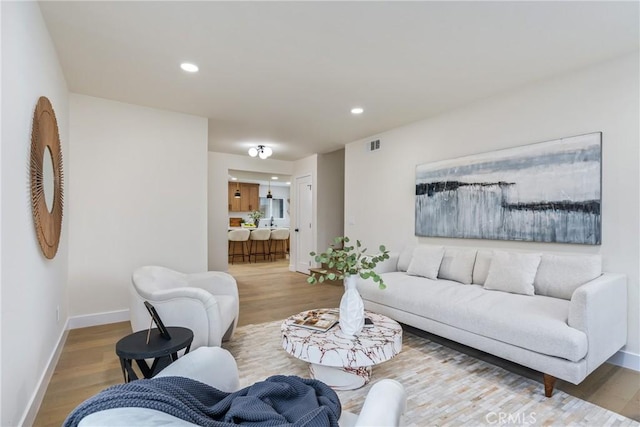 living room featuring visible vents, baseboards, wood finished floors, and recessed lighting